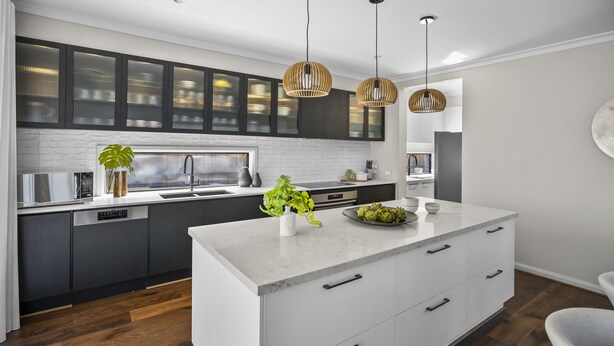 A modern kitchen with dark cabinets, a white island, and wooden flooring. - Werribee Luxe Home Family 6Bed Netflix (Werribee)