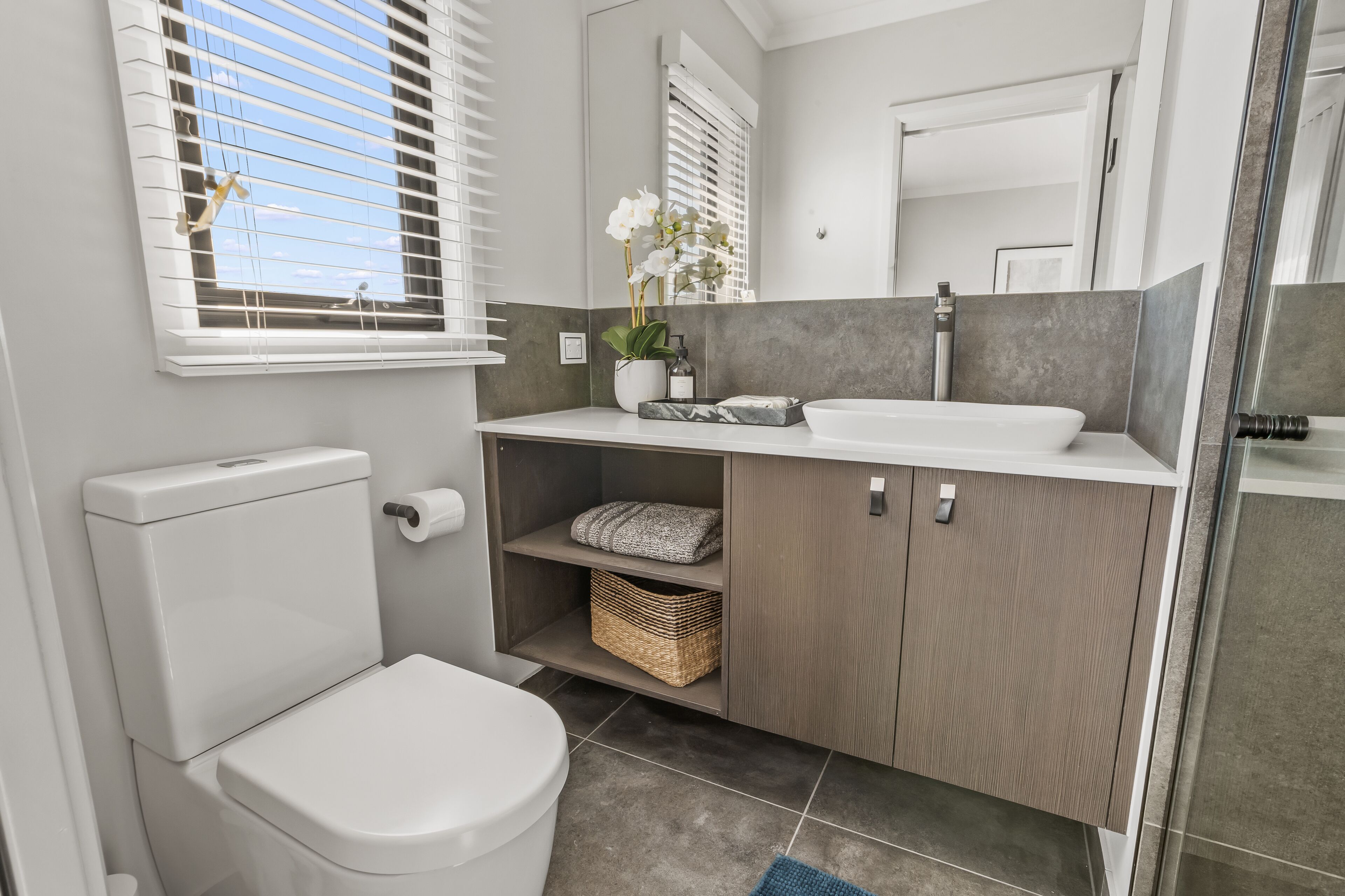 A modern bathroom with a white toilet, a sink, and a shower area.