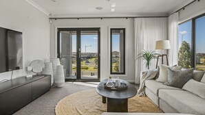 A modern living room with a sofa, a coffee table, and a TV on a black cabinet. - Werribee Luxe Home Family 6Bed Netflix (Werribee)