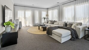 A modern living room with a sofa, coffee table, and a TV on a stand. - Werribee Luxe Home Family 6Bed Netflix (Werribee)