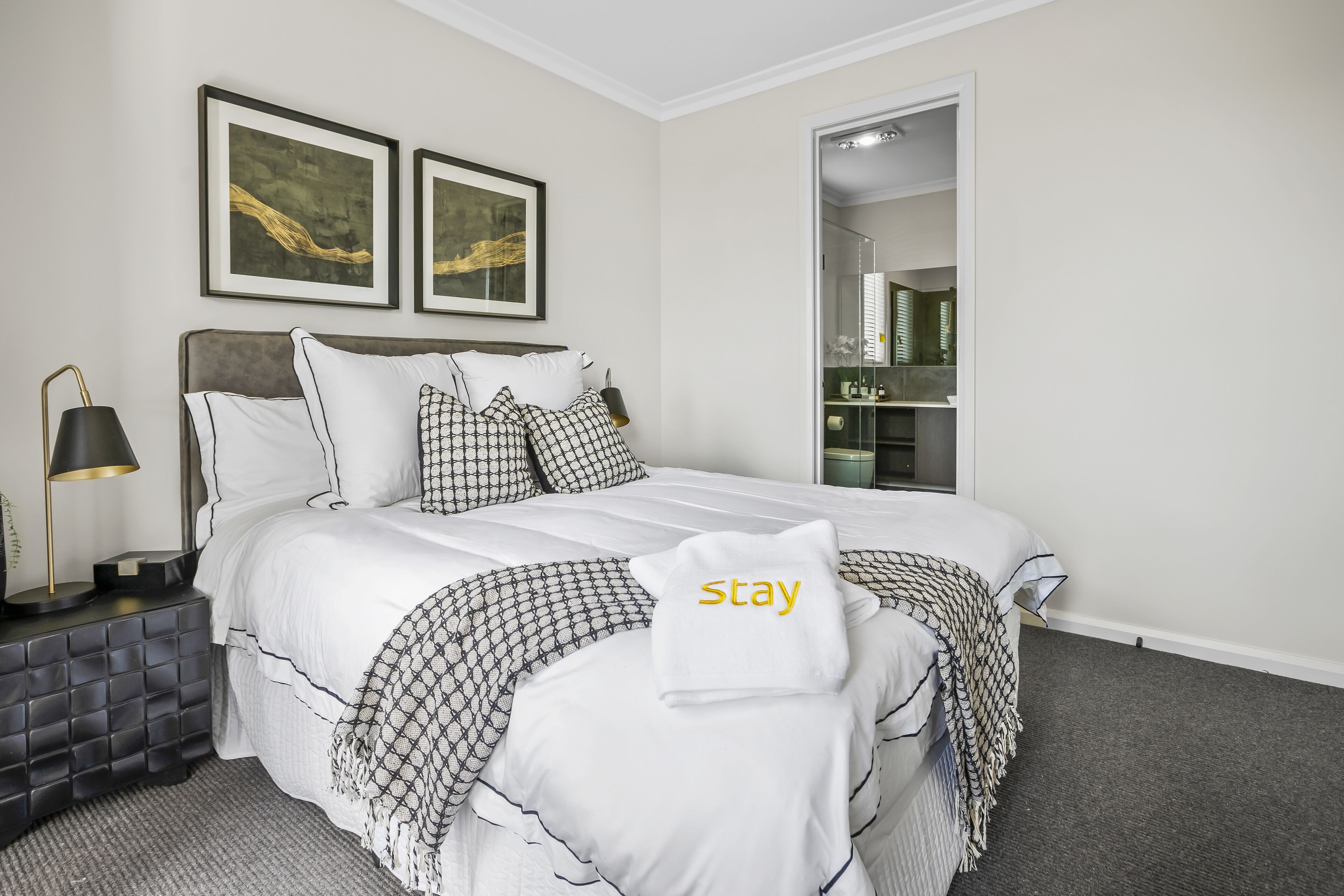 A neatly arranged hotel room with a bed, a nightstand, a lamp, and a wardrobe.
