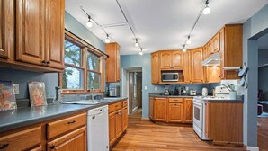 A kitchen with wooden cabinets, a dishwasher, a microwave, and a stove. - Escape To The Countryside At Black Oak Farm (Mount Carroll)