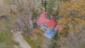 A two-story house with a red roof, surrounded by trees and a dirt path. - Escape To The Countryside At Black Oak Farm (Mount Carroll)