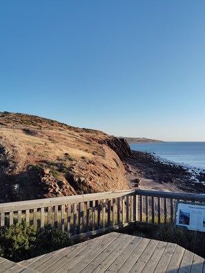 Un passeig de fusta que condueix a una riba rocosa amb vista clara a l'oceà.