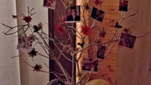 Ein Zimmer mit Holzboden, einer dekorativen Pflanzenanordnung und einer herzförmigen Lichterfolge, die 'FIBD' auf dem Boden zeigt.
