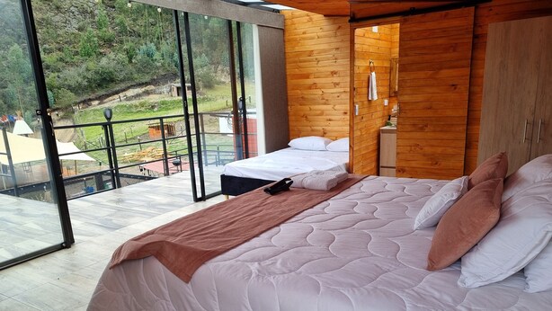 Ein Schlafzimmer mit einem großen Bett, einem Holzschrank und Blick auf einen Garten durch eine Glastür.