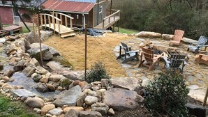 Una cabaña rústica con una terraza de madera y un área con hogar de piedra.