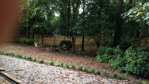 A garden area with a gravel path, wooden chairs, and a wooden fence.