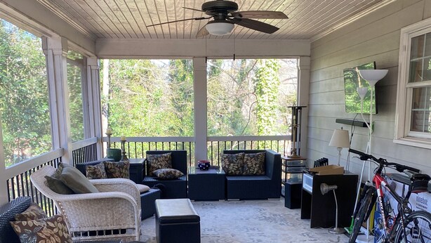 A covered porch with wicker furniture, a ceiling fan, and a bicycle.