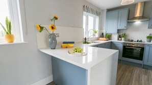 Een moderne keuken met een wit aanrechtblad, blauwe kastjes en een ingebouwde oven.