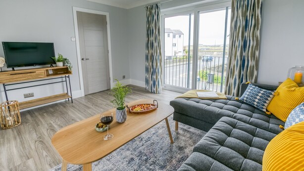 Een moderne woonkamer met een bank, een salontafel en een televisie op een houten dressoir.
