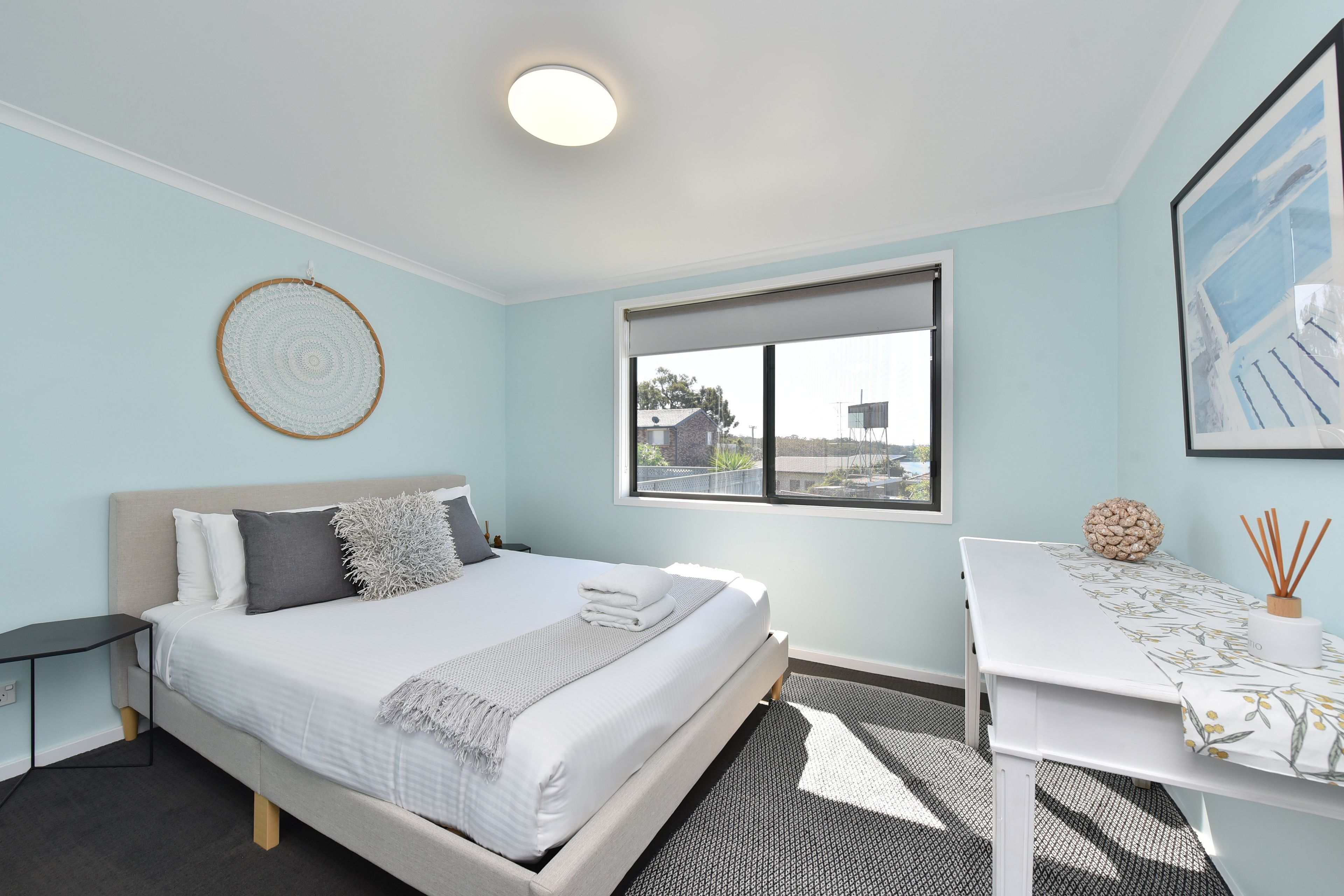 A modern bedroom with a bed, bedside table, and a window with a view.
