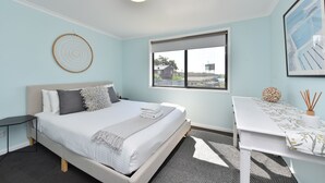 Une chambre moderne avec un lit, une table de chevet et une fenêtre donnant sur un beau paysage.
