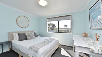 A modern bedroom with a bed, bedside table, and a window with a view.