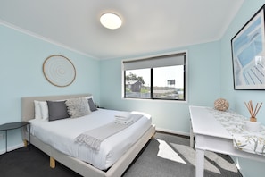 Un dormitorio moderno con cama, mesita de noche y ventana con vistas.