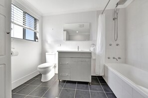 A modern bathroom with a toilet, vanity, and bathtub.
