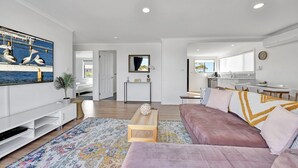 Un salon moderne avec un canapé, une table basse et un téléviseur. Il y a également un coin cuisine avec une table à manger et des chaises.