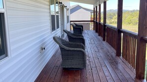 A covered porch with wooden flooring and wicker chairs.