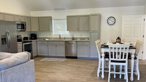 A modern kitchen with a dining area, wooden flooring, and a ceiling fan.