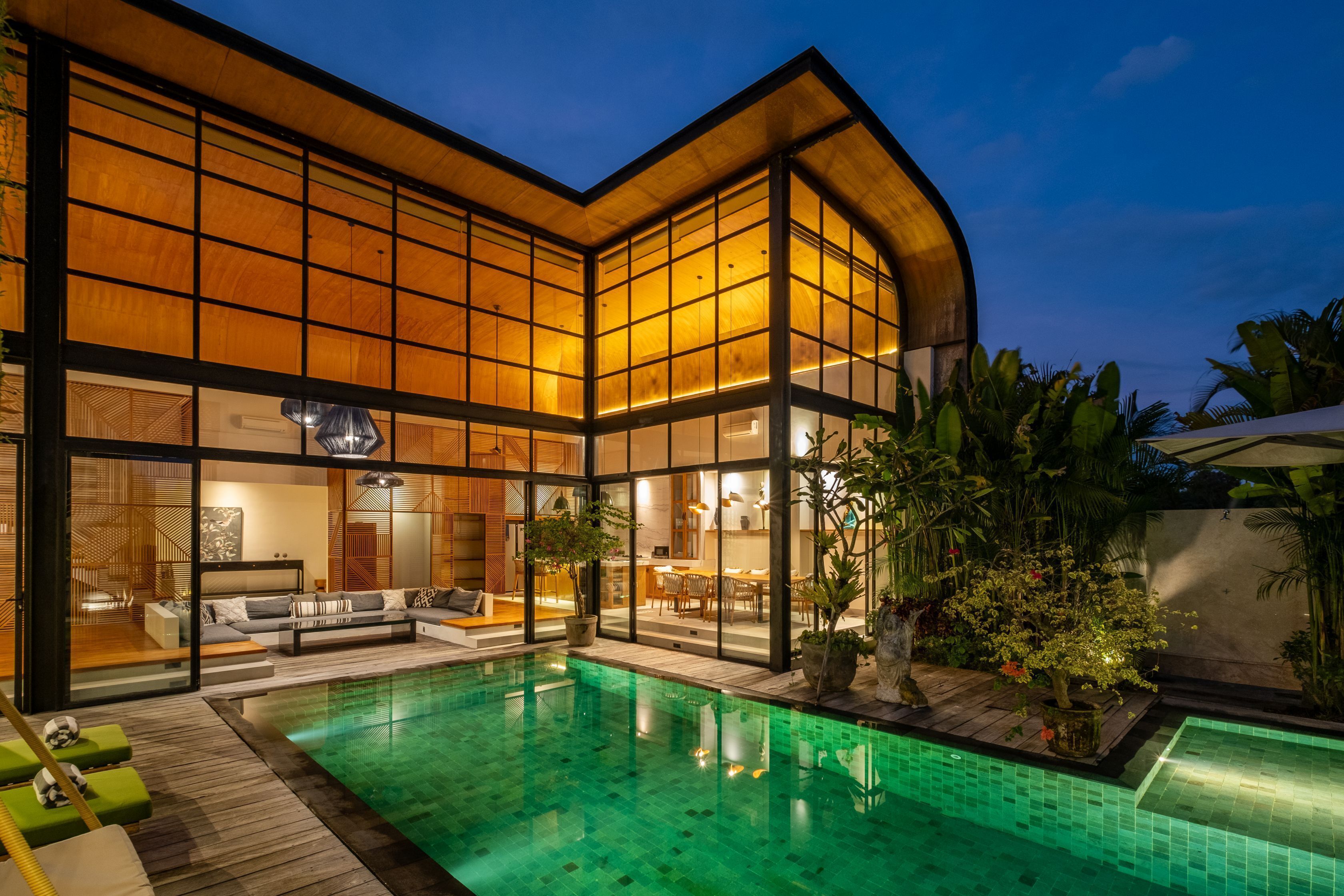 Ein modernes Haus mit Swimmingpool, großen Fenstern und einem hellen Innenraum.