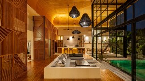 A modern interior with a wooden ceiling, a dining area, and a view of an outdoor pool. - Villa Gaia Pererenan (Canggu)
