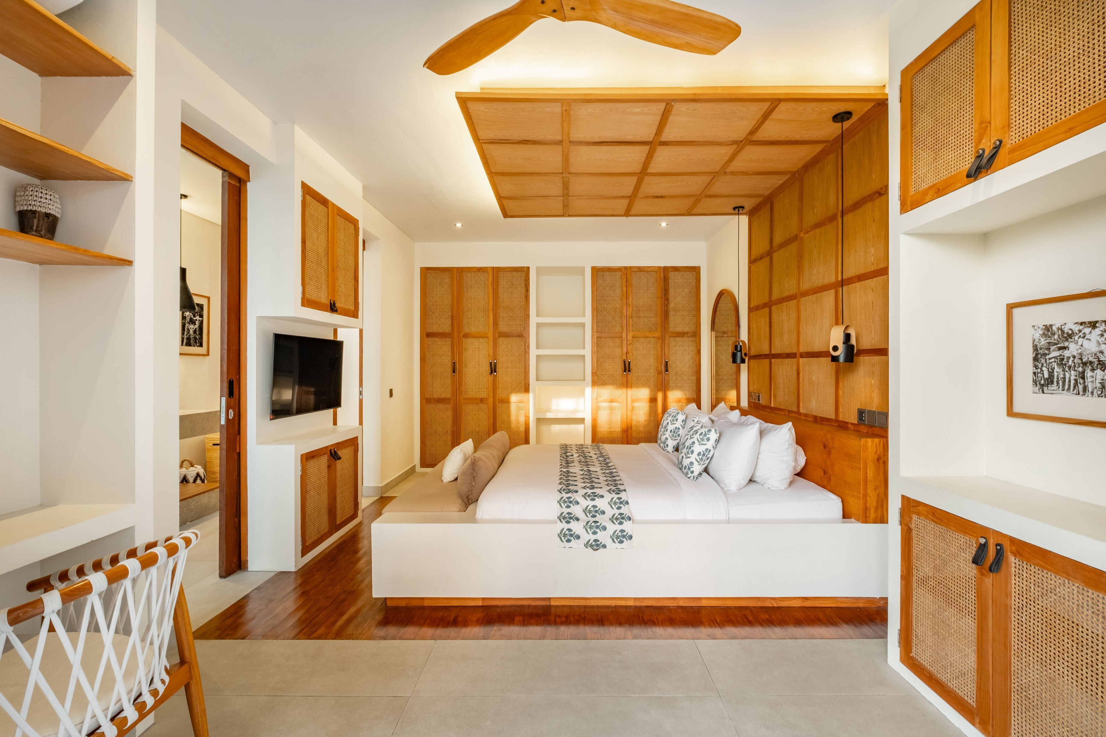 Une chambre spacieuse avec un grand lit, des lambris en bois, un ventilateur de plafond et un téléviseur.