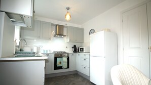 Une cuisine moderne avec des meubles blancs, un four à micro-ondes, une cuisinière et un réfrigérateur.