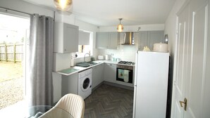 Une cuisine compacte équipée d’un lave-linge, d’un évier, d’une cuisinière et d’un réfrigérateur.
