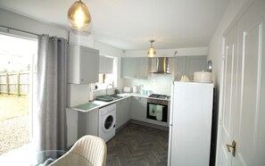Una cocina compacta con lavadora, fregadero, estufa y refrigerador.