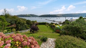 Un paisaje costero con un puerto deportivo, barcos y abundante vegetación.
