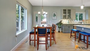 A modern kitchen with a central island, wooden dining table, and chairs. - Centrally located in UMed District. Steps from AK Air Venue, Prov/ANMC Hospitals (Anchorage)