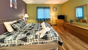 Un dormitorio con cama, lámparas de noche, televisión, un reloj y un espejo.