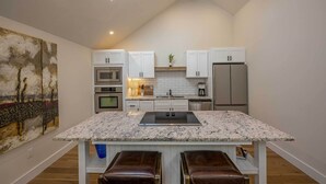 Une cuisine moderne avec des armoires blanches, un plan de travail en granit et un puits de lumière.