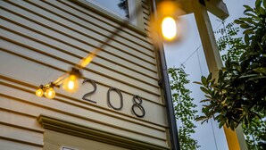 Le numéro 208 est affiché sur un immeuble de couleur beige, avec une fenêtre en dessous.