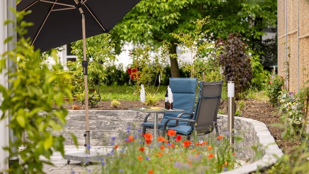Ein Sitzbereich im Freien mit Tisch, Stühlen und einem großen Sonnenschirm.