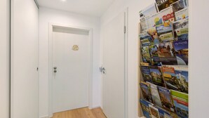Ein Flur mit einer weißen Tür und einer Wand, an der verschiedene Reisebroschüren ausliegen.
