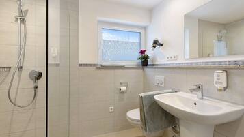 Un bagno con doccia, wc, lavandino e finestra.