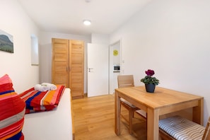 A small, bright room with a wooden door, a white wall, and a wooden table with a chair. - Spacious Holiday Apartment Maja (Mössingen)