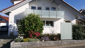 Une maison à deux étages dotée d’un balcon, d’un mur en pierre et d’une variété de plantes.