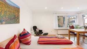 Une chambre à coucher avec un lit, des oreillers, une chaise, une table et une fenêtre donnant sur un paysage.