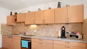 A kitchen with wooden cabinets, a dishwasher, an oven, a coffee maker, and a radio. - Apartment 'Haus Steigstrasse' with Mountain View, Private Terrace and Wi-Fi (Opfenbach)