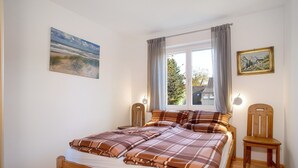 A bedroom with a bed, a chair, a window with curtains, and two wall-mounted lamps. - Apartment 'Haus Steigstrasse' with Mountain View, Private Terrace and Wi-Fi (Opfenbach)