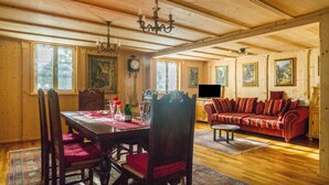 Ein Essbereich mit Holztisch, Stühlen, einer Chandelierleuchtre und einem roten Sofa.