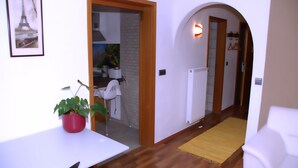 Ein Flur mit einem weißen Tisch, einem roten Blumentopf, einem gelben Teppich und einem weißen Stuhl.