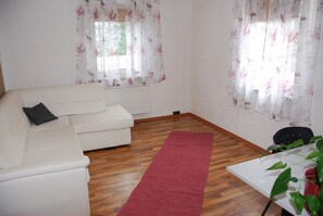 A living room with a white sofa, a red rug, and a table with a plant. - Holiday Apartment "Familienapartment Komfort" with Shared Terrace & Wi-Fi (Oberasbach)