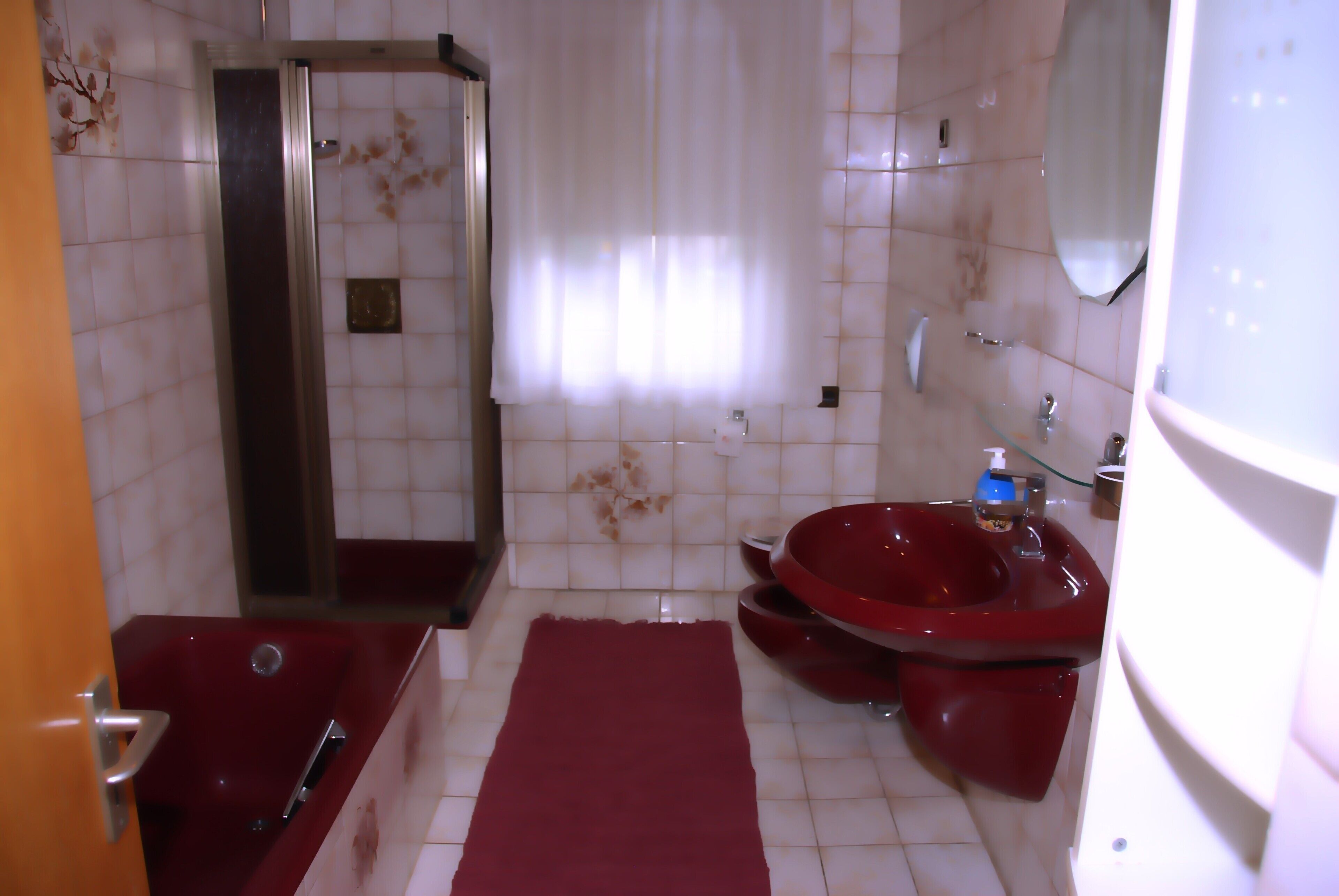 A bathroom with a bathtub, a red sink, and a shower.