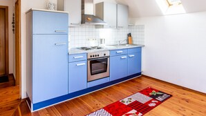 A kitchen with blue cabinets, a stainless steel oven, a window, and a wooden floor. - Apartment 'Elstar' with Wi-Fi (Stockach)