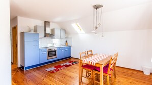 A compact kitchen with blue cabinets, a dining table with chairs, and a red rug. - Apartment 'Elstar' with Wi-Fi (Stockach)