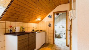Una cocina con techo de madera, armarios blancos y piso de baldosas.
