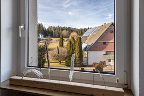 A window with a view of a rural landscape, including houses, trees, and solar panels on rooftops. - Apartment 'Ferienwohnung Hüttennest' (Villingen-Schwenningen)
